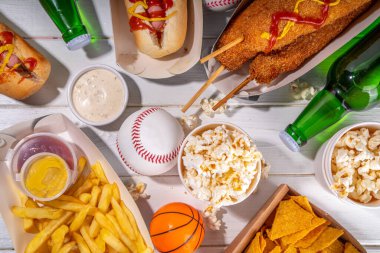 Geleneksel spor stadyumu yemekleri ve bira arka planı, çeşitli beyzbol, basketbol, futbol fanatikleri ve stadyum atıştırmalıkları, cips, sos, bira şişeli sosisliler ve fan aksesuarları. 