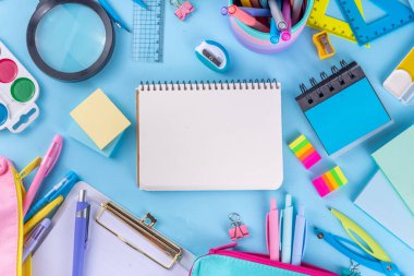 Okul ekipmanları parlak mavi düz yerde yatıyordu. Çeşitli okul ve ofis malzemeleri, aksesuarlar. Okul satışına geri dön. Üst görünüm kopyalama alanı