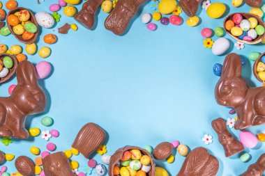 Easter chocolate egg and bunny background. High-colored flat lay with chocolate bunny and rabbits, colorful chocolate eggs. Preparation for Easter, greeting card, Easter sale, top view copy space