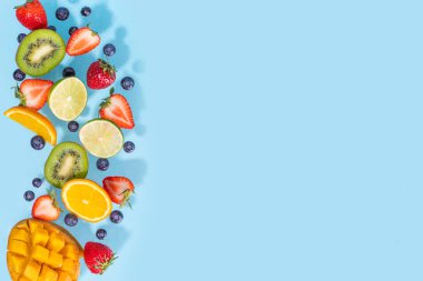 Yaz vitamini yiyecekleri, çeşitli meyveler, mango şeftali, şeftali, nane, kayısı, üzümlü üzümlü üzümlü üzümler, açık mavi arka planda uzanan kreatif düz fotokopi alanı.
