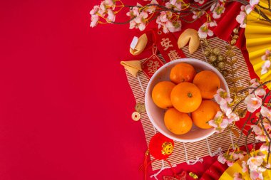 Kopya alanı olan Çin Yeni Yıl temalı arka plan. Kırmızı fanlar, altın sikkeler, mandallar, kiraz çiçekleri, bayram altın dalları, dekorlar, dilek zarfları. Kırmızı arka planda altın ejder 