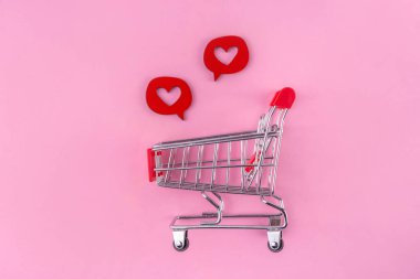 Kalp şeklinde hediye kutusu olan alışveriş arabası. Pembe ve beyaz arka plan, fotokopi alanı. Sevgililer günü hediyeleri alışveriş konsepti fotokopi alanı