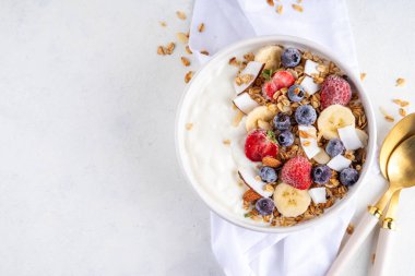 Lezzetli sağlıklı dengeli kahvaltı veya meyveli yoğurt tanecikleri - muz, çilek, yabanmersini, badem, hindistan cevizi dilimleri kopyalama alanı