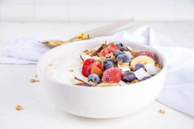 Lezzetli sağlıklı dengeli kahvaltı veya meyveli yoğurt tanecikleri - muz, çilek, yabanmersini, badem, hindistan cevizi dilimleri kopyalama alanı