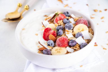 Lezzetli sağlıklı dengeli kahvaltı veya meyveli yoğurt tanecikleri - muz, çilek, yabanmersini, badem, hindistan cevizi dilimleri kopyalama alanı