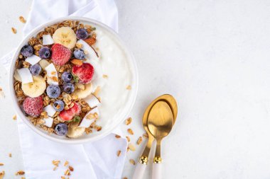 Lezzetli sağlıklı dengeli kahvaltı veya meyveli yoğurt tanecikleri - muz, çilek, yabanmersini, badem, hindistan cevizi dilimleri kopyalama alanı