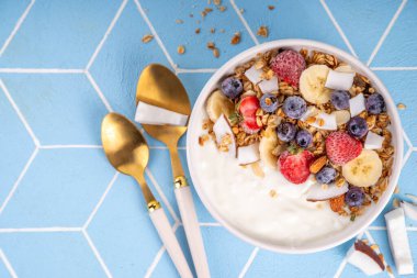 Lezzetli sağlıklı dengeli kahvaltı veya meyveli yoğurt tanecikleri - muz, çilek, yabanmersini, badem, hindistan cevizi dilimleri kopyalama alanı