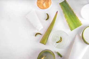  Aloe vera skin are güzellik bakım düz yatıyordu. Çeşitli şişeler, aloe kremli kavanozlar, beyaz arka planda taze aloe yapraklı jel serumu, ev yapımı organik yeşil kozmetik ürünleri.