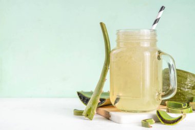 Cam bardak ev yapımı aloe vera suyu beyaz beton masa üzerinde taze aloe yaprakları, kopyalama alanı