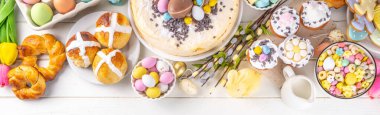 Easter brunch, breakfast food, Kids Easter party buffet. Various traditional Easter sweets, candy, pasties and baking - cross buns, cheesecake, chocolate eggs, pancakes, cupcakes, top view copy space
