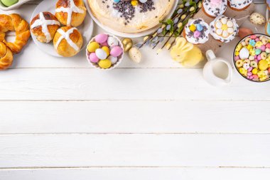 Easter brunch, breakfast food, Kids Easter party buffet. Various traditional Easter sweets, candy, pasties and baking - cross buns, cheesecake, chocolate eggs, pancakes, cupcakes, top view copy space