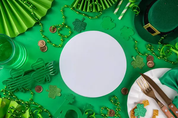 Saint Patrick masa takımı çatal bıçak, bıçak ve çatal, Patrick günü dekorasyonu, bozuk paralar, leprikon şapkası, gözlükler, şanslı at nalı, konfeti, yeşil arka planda boncuklar.
