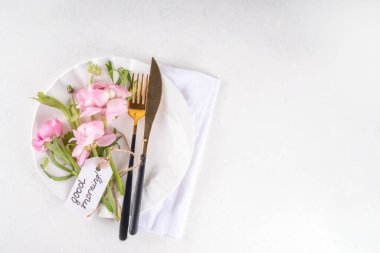 Yumuşak pembe çiçekli bahar tatili masası seti, çatal bıçak, tabak, bıçak, beyaz zemin üzerinde çatal etiket ile Günaydın, üst görünüm kopyalama alanı