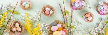 Paskalya yuvaları ve bahar çiçekli yumurtalar, Mutlu Paskalya bayramı tebrik kartları açık yeşil bahar arka planında yatıyordu, üst görünüm kopyalama alanı