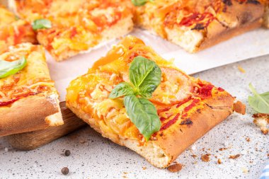 Domates ve fesleğenli ev yapımı margarita pizza, malzemeler ve arka planda beyaz mutfak masasında zeytinyağı.