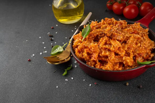 Domates soslu Mafaldine makarnası, İtalyan bolonezi, domates soslu marinara, vegan mantarı ya da siyah beton arka planda patlıcan soslu makarna, malzemeler ve baharatlar, kopyalama alanı.