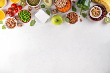 Portföy diyeti, fındık, sebze proteini, bitki sterolleri, yapışkan lif, fasulye, baklagiller, taze sebzeler ve beyaz arka plandaki meyveler dahil olmak üzere dengeli kolesterol vejetaryen gıdalar.