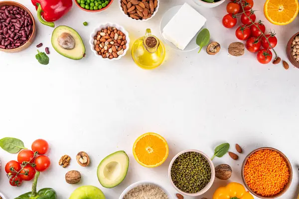 Portföy diyeti, fındık, sebze proteini, bitki sterolleri, yapışkan lif, fasulye, baklagiller, taze sebzeler ve beyaz arka plandaki meyveler dahil olmak üzere dengeli kolesterol vejetaryen gıdalar.