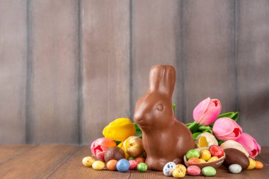 Paskalya arkaplan tebrik kartı, geleneksel şekerleme, Paskalya yumurtası avı eğlence konsepti. Çikolata tavşanı, çikolata ve şeker Tahta arka planda Paskalya yumurtası