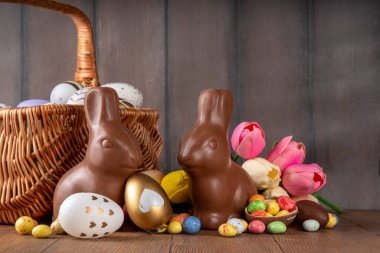 Paskalya arkaplan tebrik kartı, geleneksel şekerleme, Paskalya yumurtası avı eğlence konsepti. Çikolata tavşanı, çikolata ve şeker Tahta arka planda Paskalya yumurtası