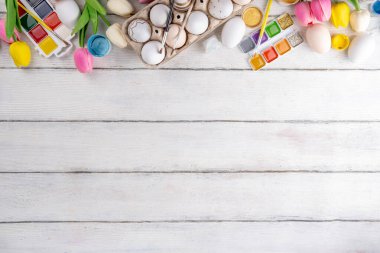 Aile gelenekleri, Paskalya hazırlıkları. Bahar çiçeği laleleri, dekoratif Paskalya yumurtaları boyalı, fırçalı, aksesuarlı beyaz ahşap arka planda yumurta çizip boyamak için aksesuarlar.