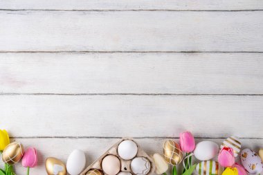 Paskalya yuvaları ve bahar çiçekli yumurtalar, Mutlu Paskalya bayramı tebrik kartları tahta arka planda yatıyordu, üst görünüm kopyalama alanı
