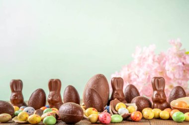 Paskalya arkaplan tebrik kartı, geleneksel şekerleme, Paskalya yumurtası avı eğlence konsepti. Çikolata tavşanı, çikolata ve şeker Tahta arka planda Paskalya yumurtası