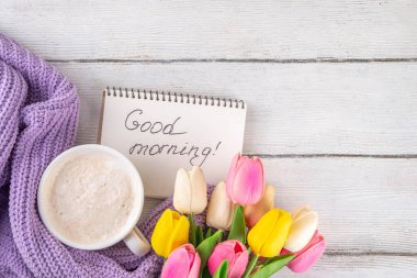 Kahve fincanı ve günaydın notu ve bir buket lale çiçeğiyle dolu bir bahar sabahı. Bahar tatili, tatil arkaplanı, tebrik kartı, üst görünüm düz kopya alanı