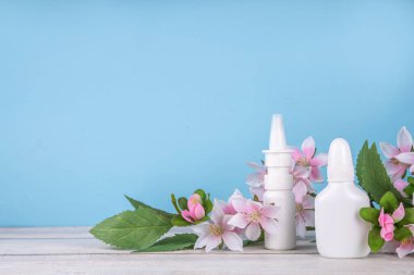 Mevsimlik bahar alerjisi konsepti. Taze bahar çiçek açan ağaç dalları, çeşitli burun alerjisi tedavileri, damlalar, alerji için sprey şişeleri, rhinitis, pollinosi, renkli arkaplanda kopyalama alanı