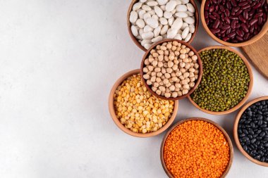 Çeşitli kuru fasulyeler, mercimek, mung, nohut, ahşap kaselerde bezelye çeşitleri. Legumes beyaz masa üst görünümünde. Vegan protein kaynakları yiyecek, kopyalama alanı