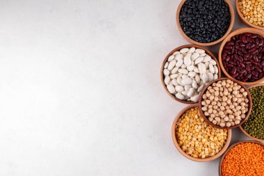 Çeşitli kuru fasulyeler, mercimek, mung, nohut, ahşap kaselerde bezelye çeşitleri. Legumes beyaz masa üst görünümünde. Vegan protein kaynakları yiyecek, kopyalama alanı