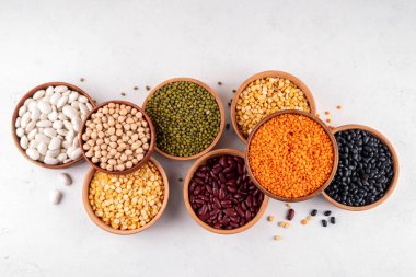 Çeşitli kuru fasulyeler, mercimek, mung, nohut, ahşap kaselerde bezelye çeşitleri. Legumes beyaz masa üst görünümünde. Vegan protein kaynakları yiyecek, kopyalama alanı