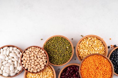 Çeşitli kuru fasulyeler, mercimek, mung, nohut, ahşap kaselerde bezelye çeşitleri. Legumes beyaz masa üst görünümünde. Vegan protein kaynakları yiyecek, kopyalama alanı