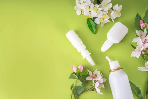 Seasonal spring allergies concept. Fresh spring blooming tree branches, various nasal allergy treatment, drops, spray bottles for allergies, rhinitis, pollinosi, copy space on colorful background