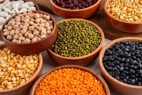 Çeşitli kuru fasulyeler, mercimek, mung, nohut, ahşap kaselerde bezelye çeşitleri. Legumes beyaz masa üst görünümünde. Vegan protein kaynakları yiyecek, kopyalama alanı