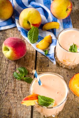 Yaz kahvaltısı içeceği, taze şeftalili smoothie, şeftalili yoğurt nektarin dilimleri, kırsal ahşap arka plan fotokopi alanı.