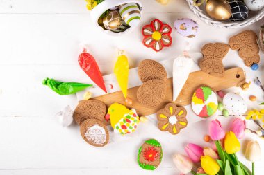 Paskalya için aile hazırlığı. Tatil pişirme arka planı, kadın ve çocuk elleri ev yapımı kurabiyeleri şekerle süsler, paskalya yumurtaları, tavşanlar, çiçekler, üst görünüm kopya alanı şeklinde.