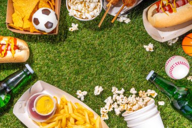 Geleneksel spor stadyumu yemekleri ve bira arka planı, çeşitli beyzbol, basketbol, futbol fanatikleri ve stadyum atıştırmalıkları, cips, sos, bira şişeli sosisliler ve fan aksesuarları. 