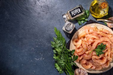 Diyet beyaz kümes hayvanlarını pişirmek. Pişirmek için taze kesilmiş tavuk şeritleri, baharatlar, otlar, siyah beton arka planda fotokopi alanı.