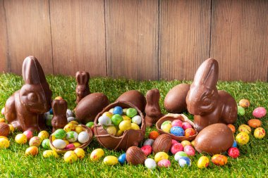 Paskalya yumurtası avcılığı geçmişi. Çeşitli şeker ve çikolatalı Paskalya yumurtası, tavşancık ve tavşanlar yeşil çimen parkında ya da bahçe arka planında yumurta sepeti