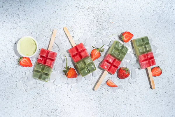 Sütsüz yeşil kibrit ve çilekli dondurma. Yeşil kibrit çay tozu ve dut suyu ile vejetaryen dondurması, beyaz beton arka planda sağlıklı organik tatlı.