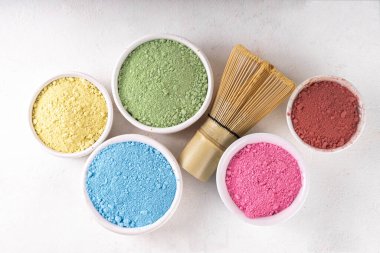 Set of dried plant matcha powder in white bowl. Various color and extracts matcha - green, yellow, pink, red, for making fruity healthy matcha tea  drinks on white background copy space clipart