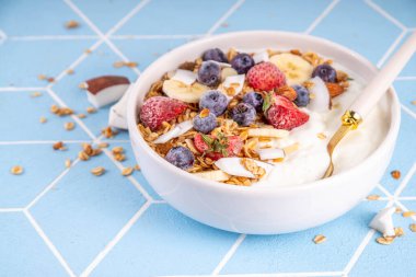 Lezzetli sağlıklı dengeli kahvaltı veya meyveli yoğurt tanecikleri - muz, çilek, yabanmersini, badem, hindistan cevizi dilimleri kopyalama alanı