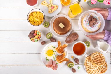 Paskalya tatili tatlı kahvaltı, brunch. Paskalya süslü Belçika waffle 'ları, krepler, kahvaltı gevrekleri ve süt, kızarmış yumurtalar kızarmış ekmek ve pastırma, Paskalya çikolatalı yumurtalar ve bahar çiçekleriyle birlikte tavşan.