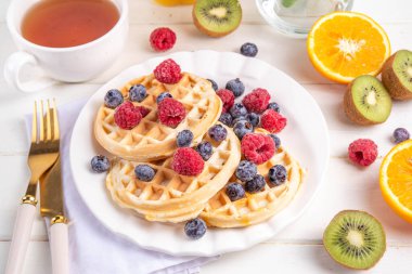 Beyaz ahşap masadaki böğürtlenli ev yapımı Belçika waffle 'ları lezzetli brunch' lar ya da Belçika waffle 'ları.