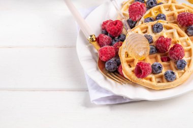 Beyaz ahşap masadaki böğürtlenli ev yapımı Belçika waffle 'ları lezzetli brunch' lar ya da Belçika waffle 'ları.