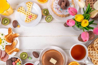 Paskalya tatili tatlı kahvaltı, brunch. Paskalya süslü Belçika waffle 'ları, krepler, kahvaltı gevrekleri ve süt, kızarmış yumurtalar kızarmış ekmek ve pastırma, Paskalya çikolatalı yumurtalar ve bahar çiçekleriyle birlikte tavşan.
