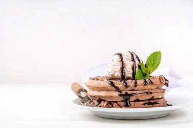 Dondurma ve çikolata soslu bir yığın çikolatalı waffle. Dondurmalı waffle, çikolata soslu çiseleme ve nane şekeri.