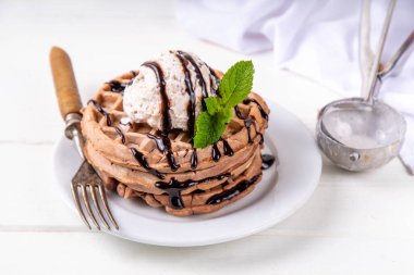 Dondurma ve çikolata soslu bir yığın çikolatalı waffle. Dondurmalı waffle, çikolata soslu çiseleme ve nane şekeri.