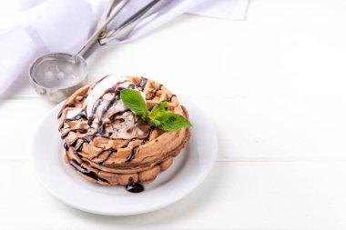 Dondurma ve çikolata soslu bir yığın çikolatalı waffle. Dondurmalı waffle, çikolata soslu çiseleme ve nane şekeri.
